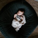 girl in white sweater and black pants lying on black round bed