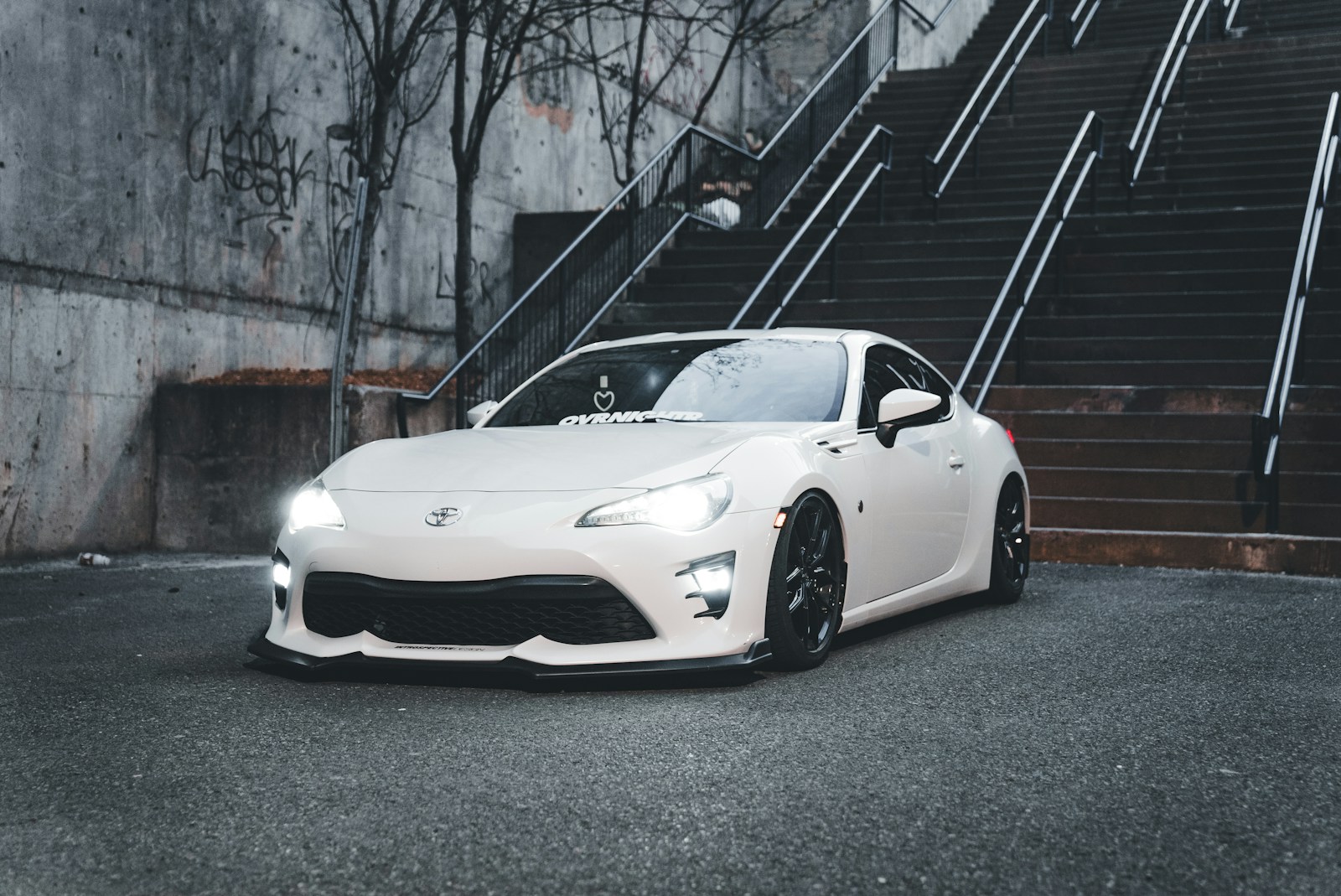 A white sports car parked in front of a set of stairs